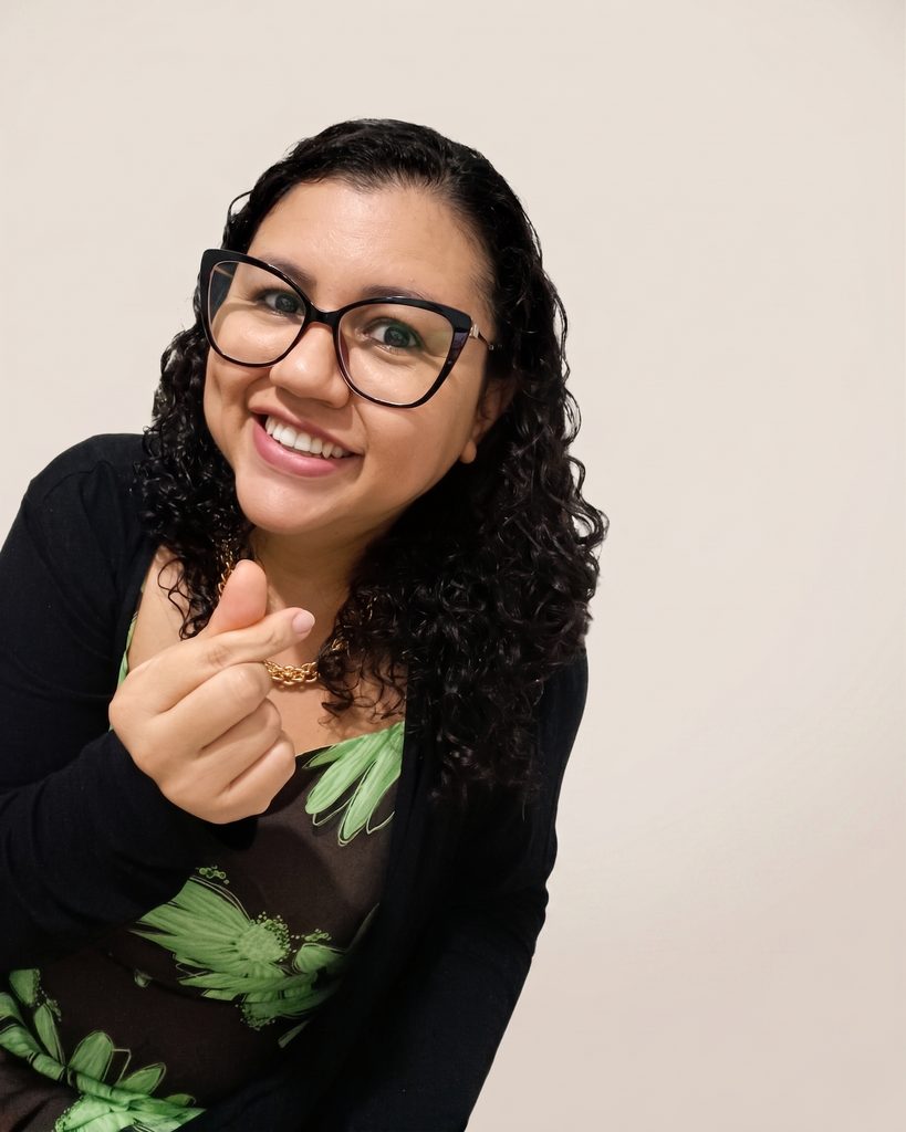 Rebeca Porto sorrindo e fazendo um coração com os dedos